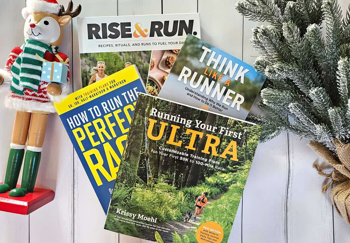 A bunch of running books next to Christmas decorations.