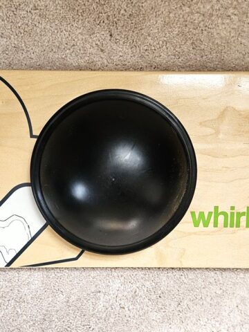 A Whirly Board balance board on the floor, showing the balance points on the bottom.