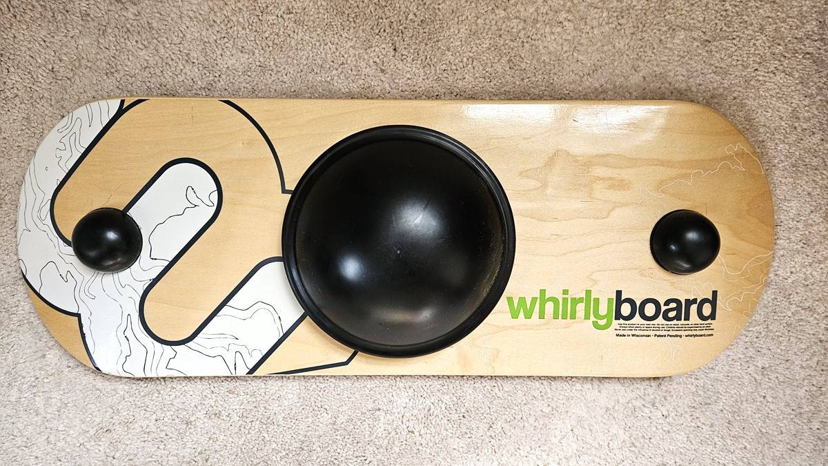 A Whirly Board balance board on the floor, showing the balance points on the bottom.