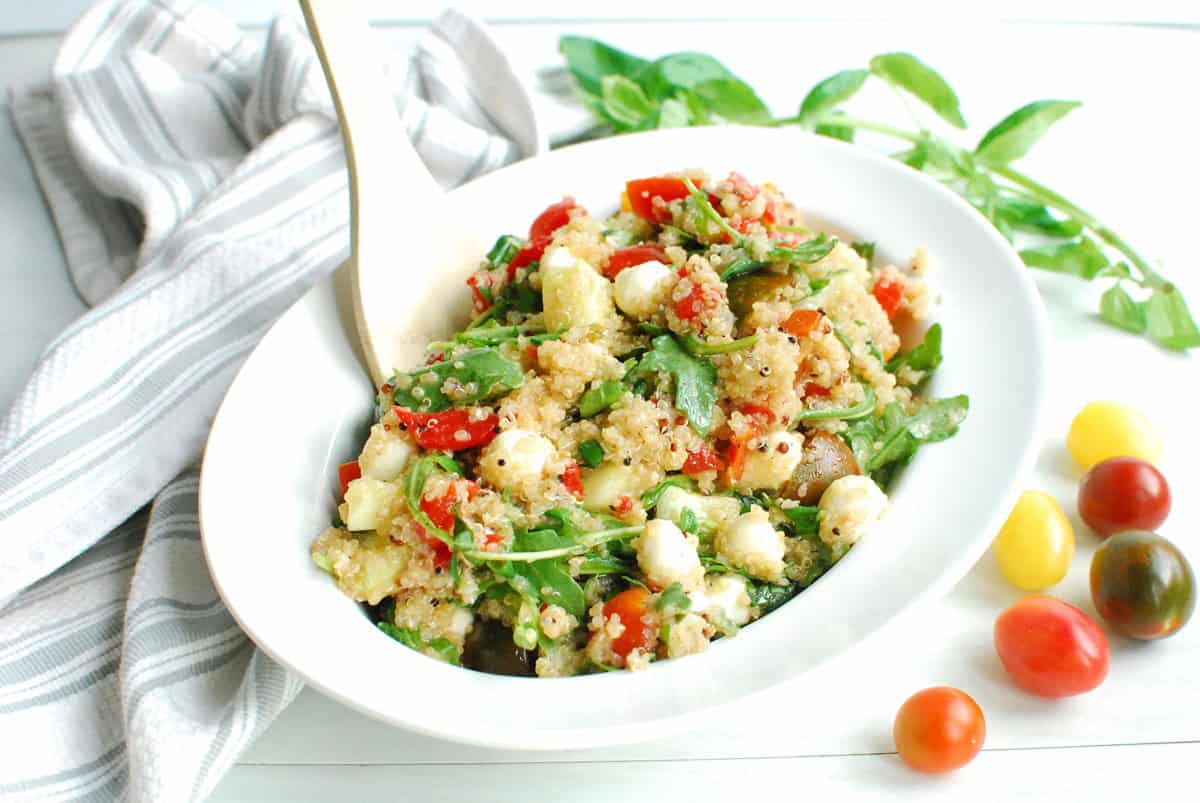 A white serving bowl full of Italian quinoa salad next to a napkin.