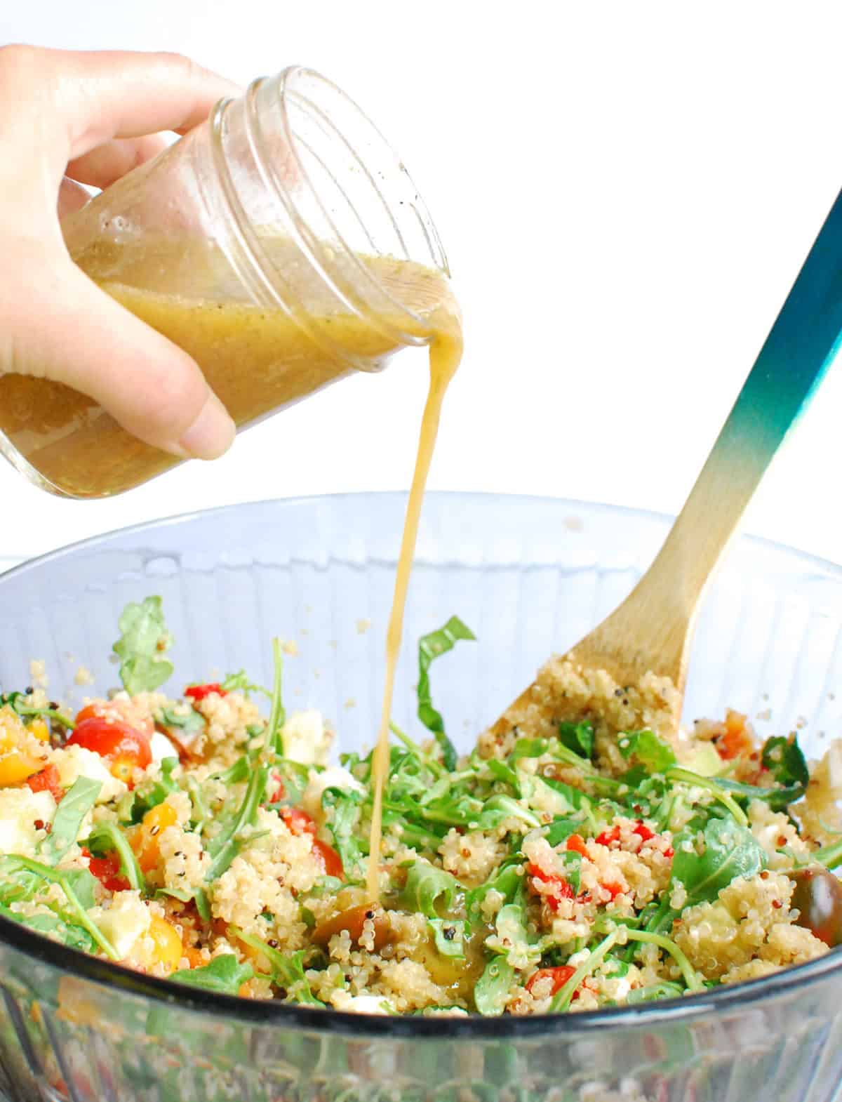 Dressing being poured onto the quinoa salad.