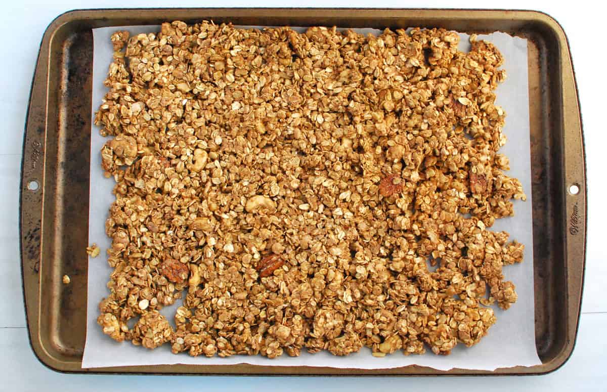 Unbaked granola on a parchment-lined baking sheet.