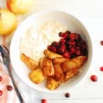 A ricotta breakfast bowl with roasted cranberries and pears next to a spoon.