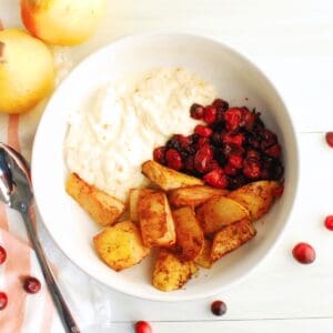 A ricotta breakfast bowl with roasted cranberries and pears next to a spoon.