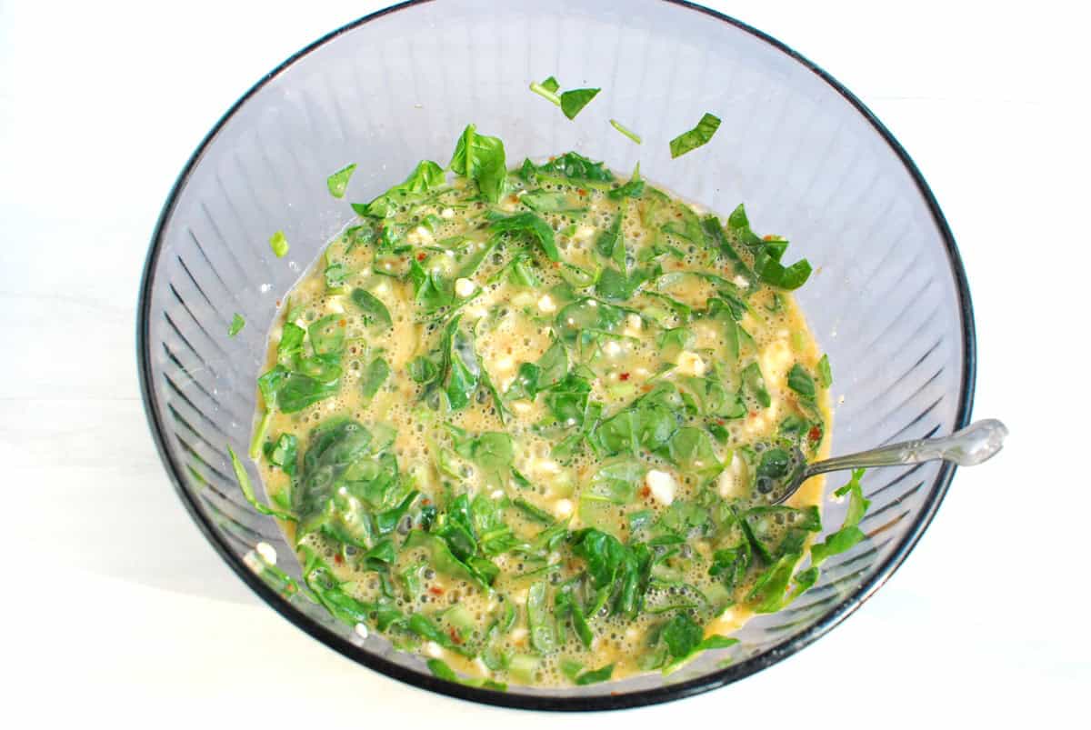 All of the ingredients for egg muffins mixed together in a large glass bowl.