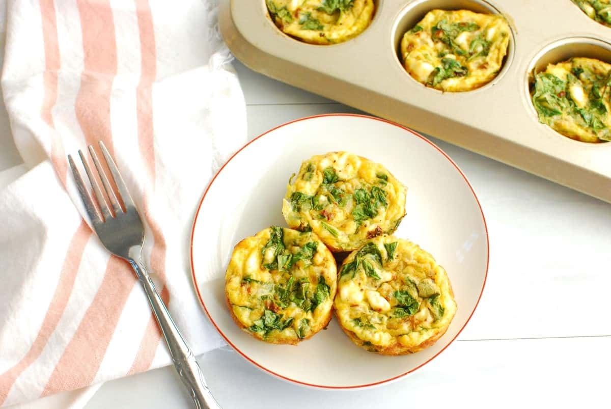 Three cottage cheese egg muffins on a plate next to a napkin and a fork.