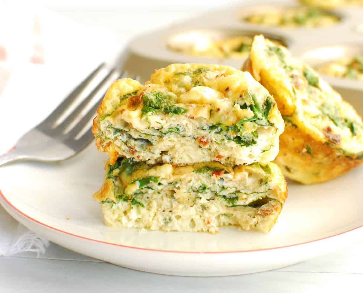 A cottage cheese egg muffin broken in half on a plate.