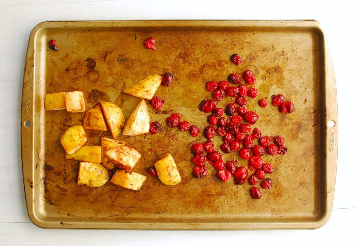 Roasted pears and cranberries on a baking sheet.