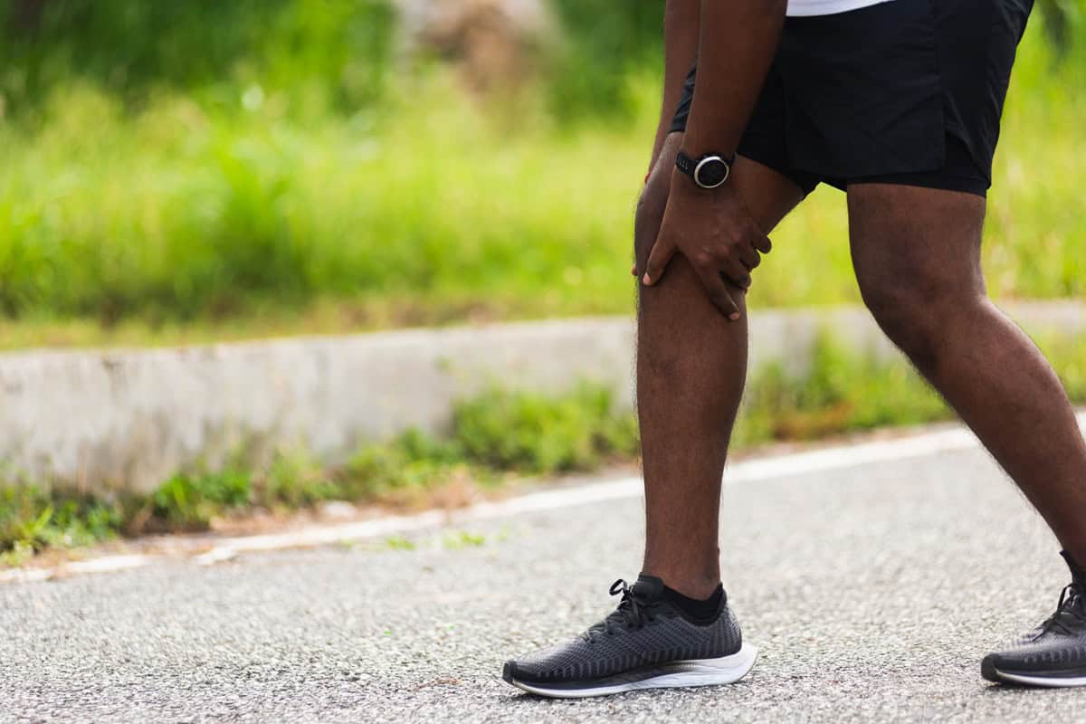 A runner holding their leg depicting an injury.