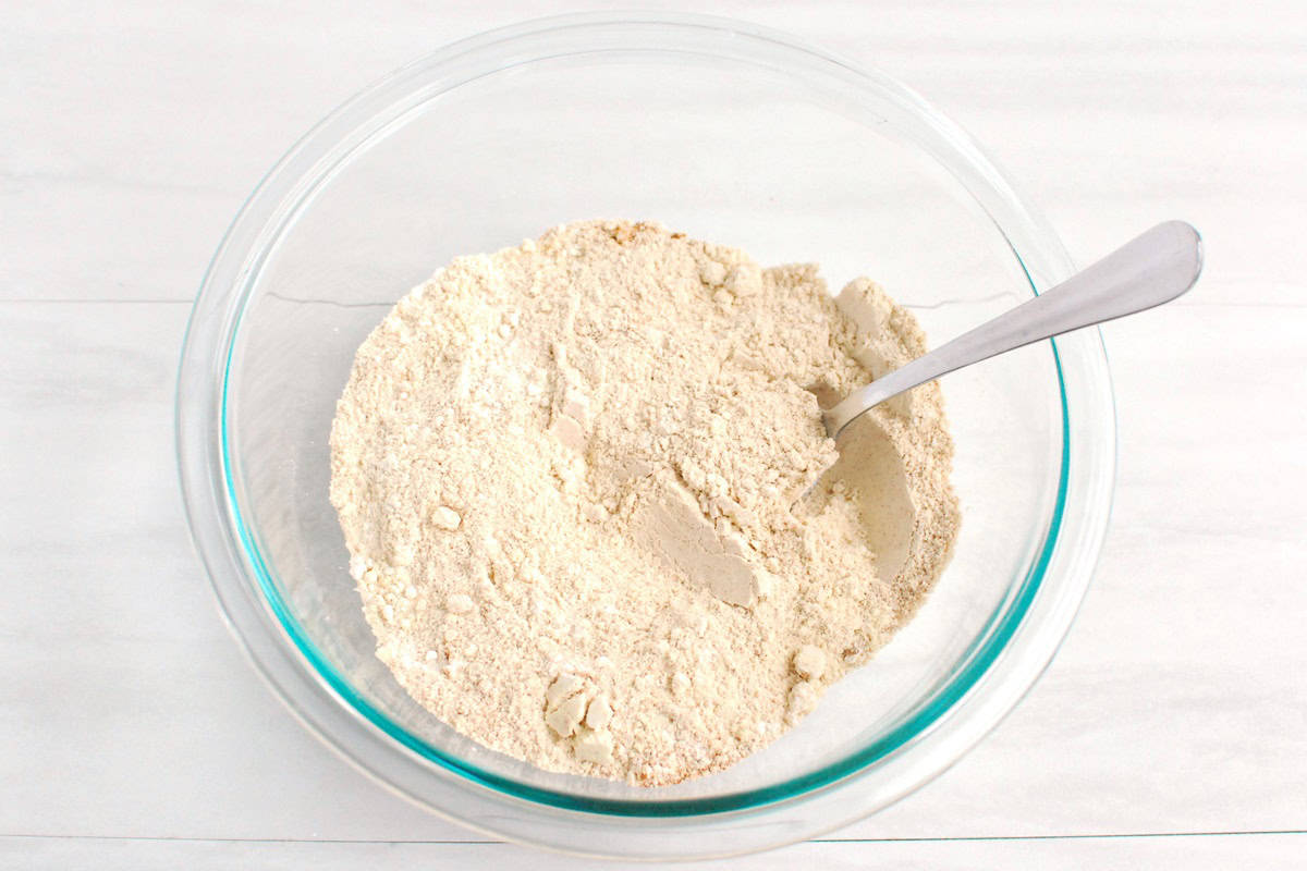 Protein powder, flour, cinnamon, baking soda, and salt mixed together in a glass bowl.