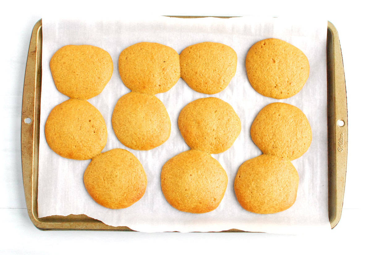 The whoopie pie cakes that were just baked on a parchment-lined baking sheet.