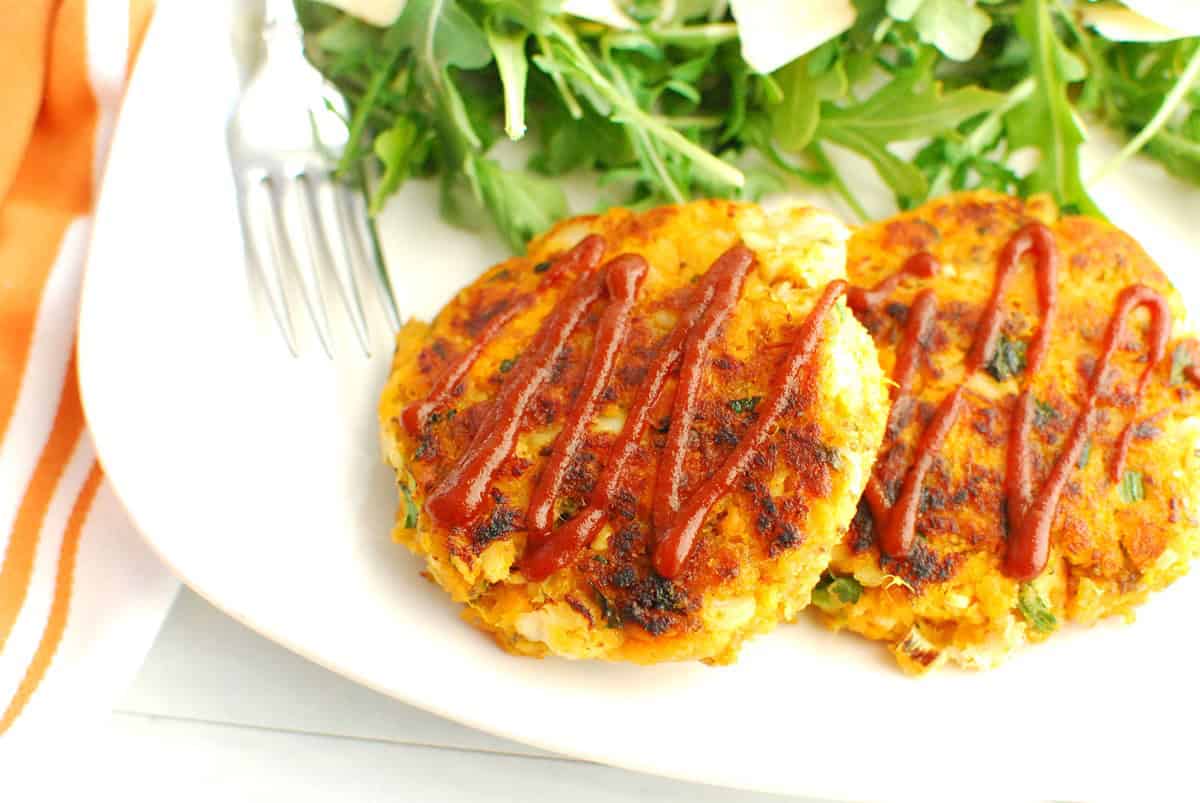 A close up of a sweetpotato fish cake topped with sriracha.