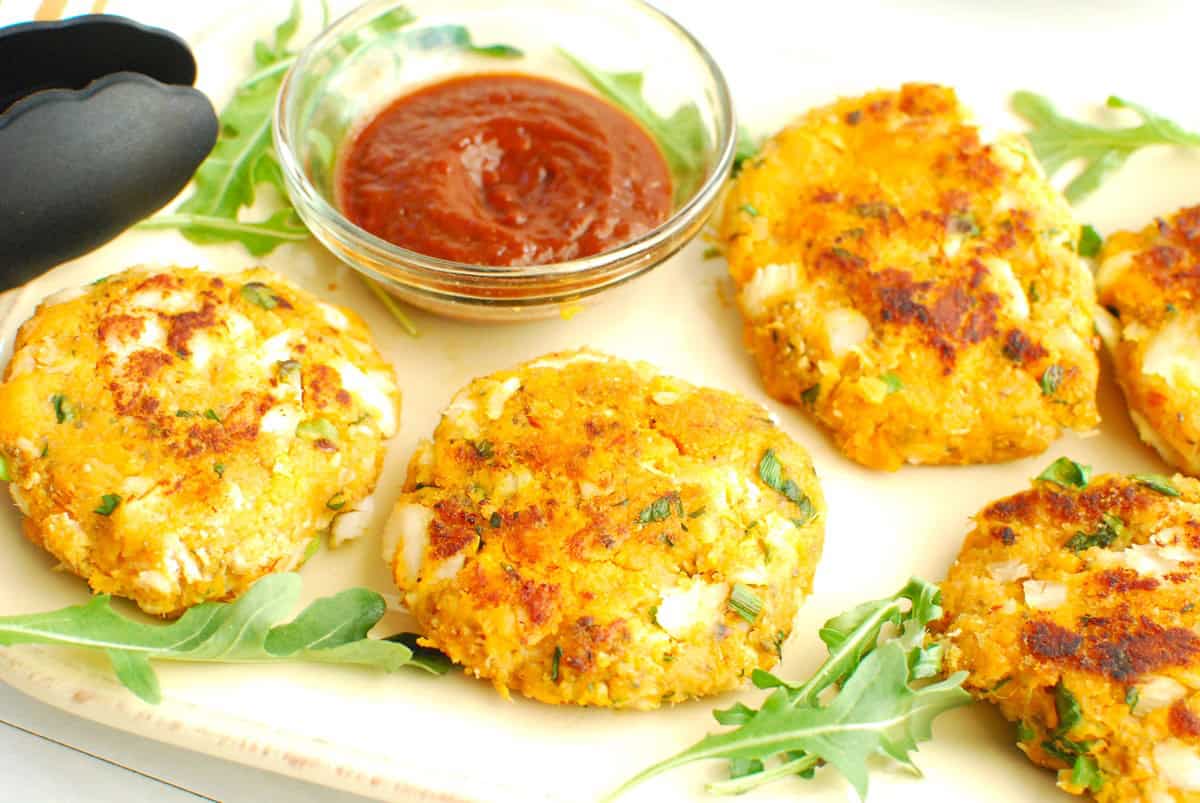 Several sweetpotato fish cakes on a platter garnished with greens.