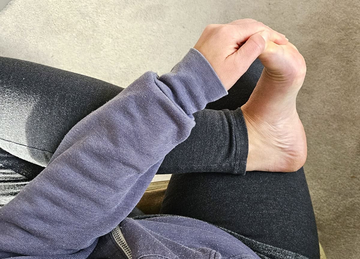 A woman holding her toes and stretching her foot.