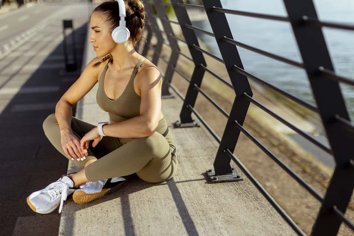 A woman sitting outside after her run.