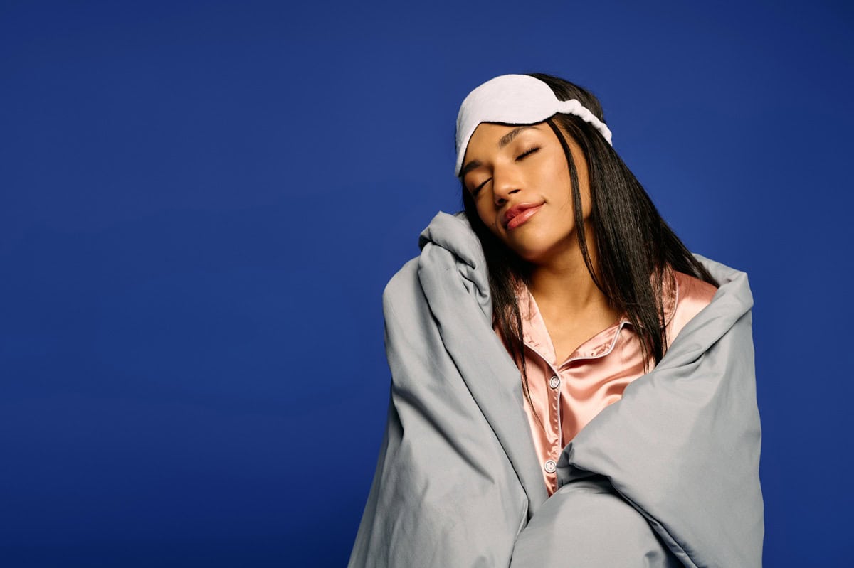 A woman looking cozy at the end of the night after doing a bedtime self-care routine.