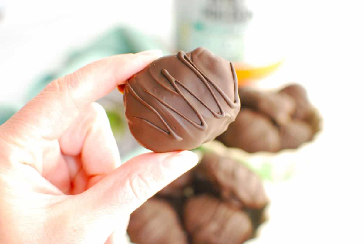 A woman's hand holding a healthy peanut butter egg.