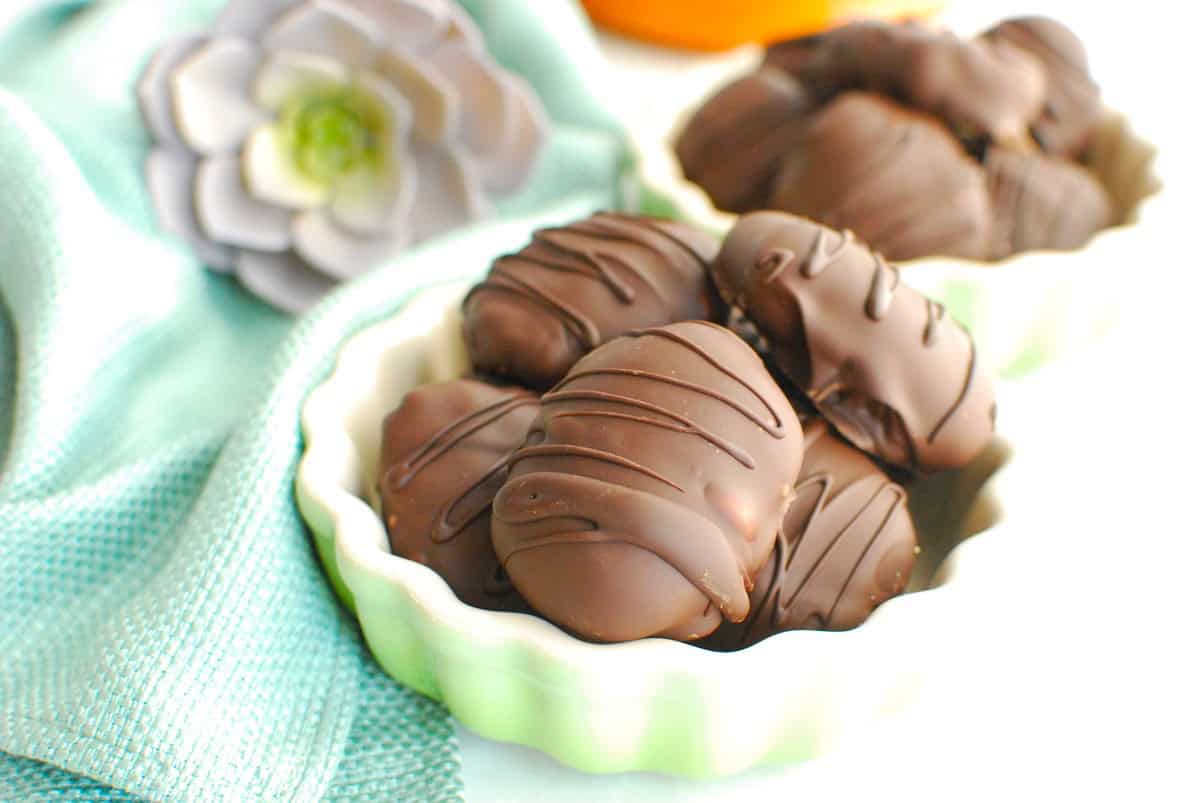 A small bowl filled with healthy chocolate-covered peanut butter eggs, next to a napkin.