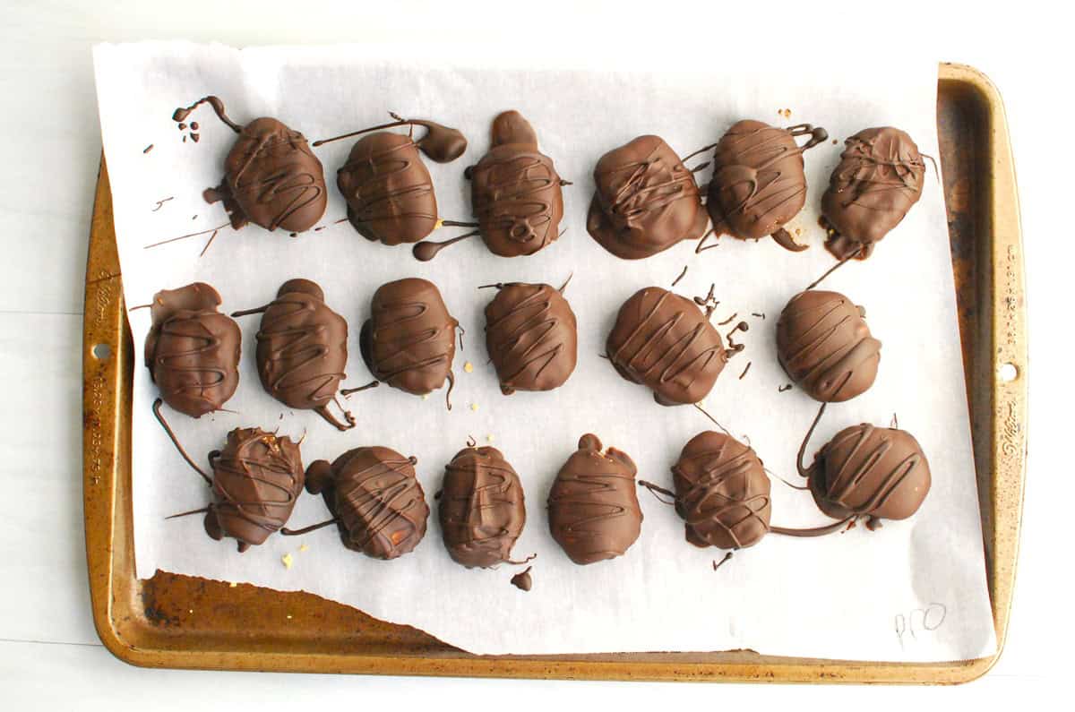 Chocolate covered peanut butter eggs on a baking sheet drizzled with extra chocolate.