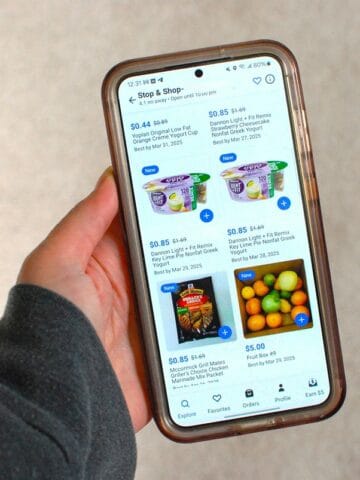 A woman's hand holding a phone displaying the Flashfood app options at one store.