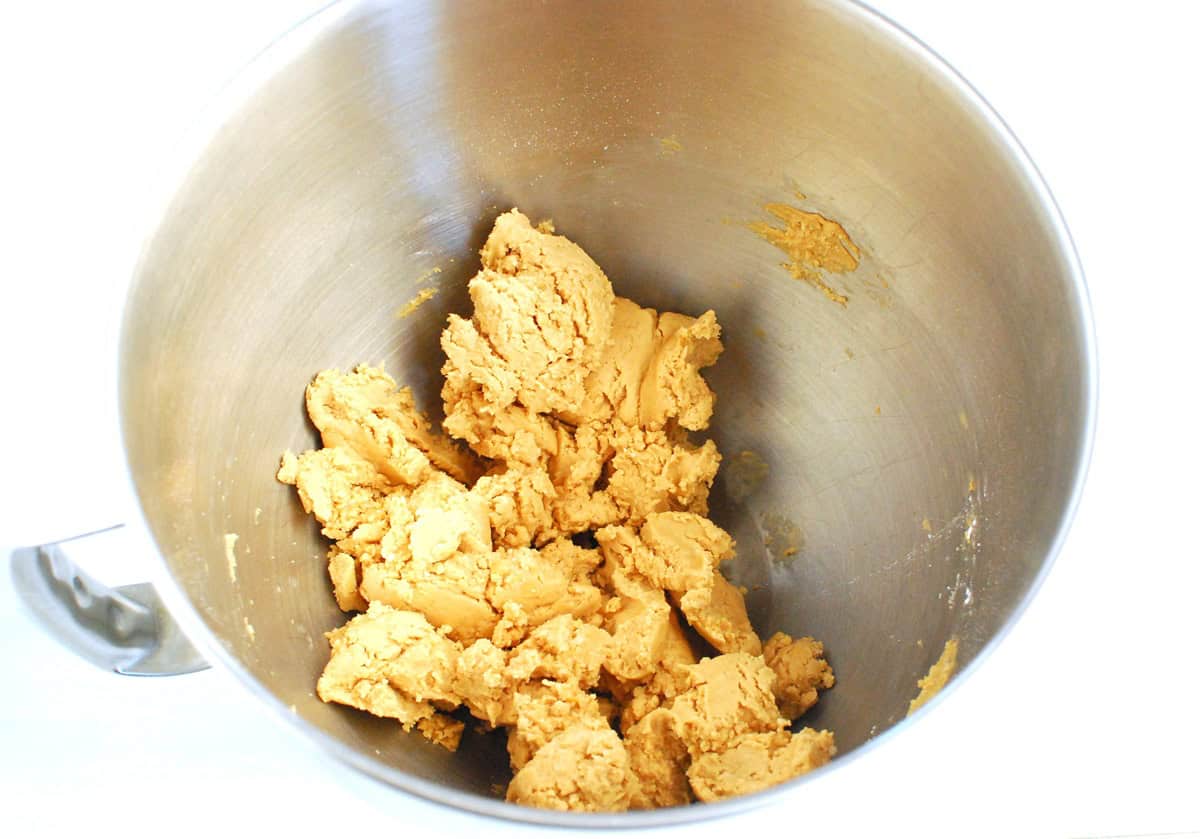 Protein powder, peanut butter, and maple syrup mixed together in a silver mixing bowl.