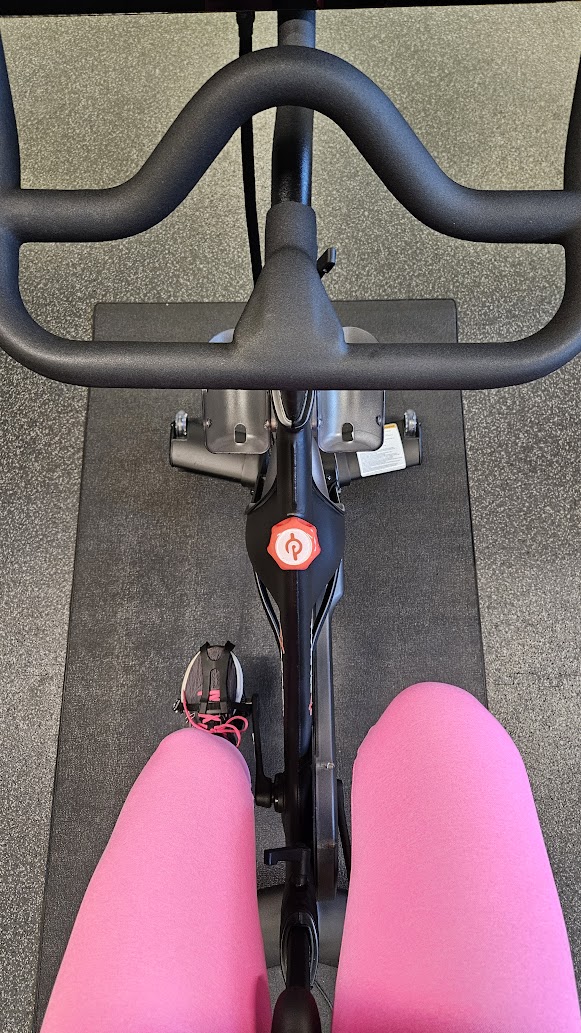 A woman riding an indoor spin bike as a cross training activity.