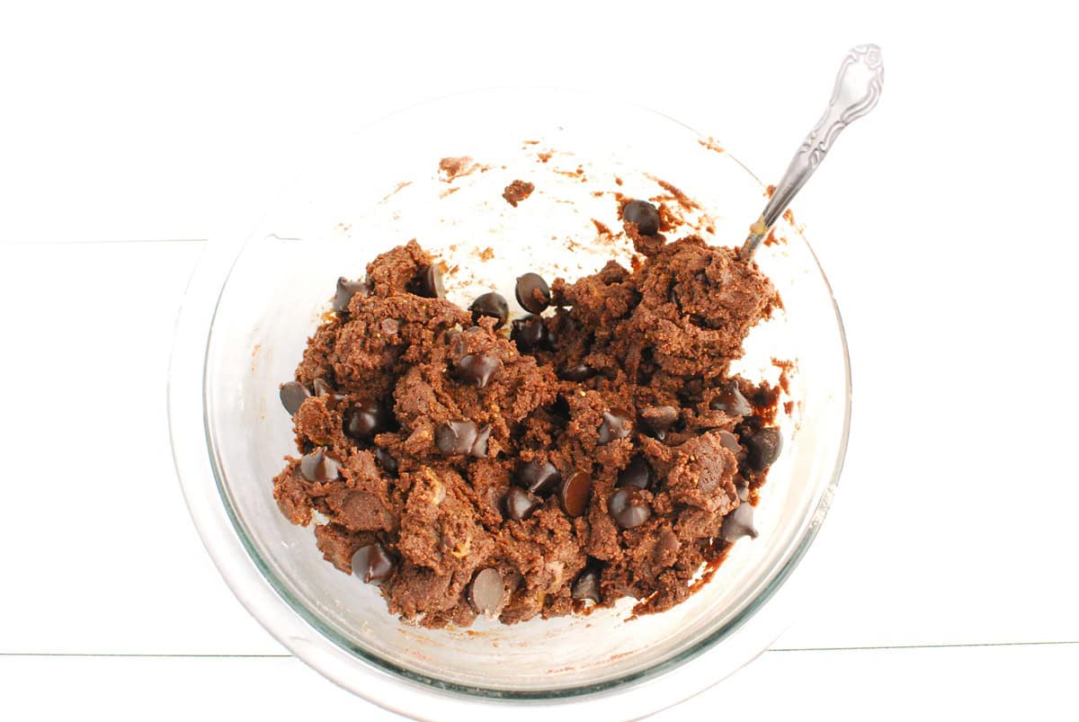 Kodiak Cakes dark chocolate pancake mix, peanut butter, melted butter, maple syrup, egg, and chocolate chips mixed together in a glass bowl.