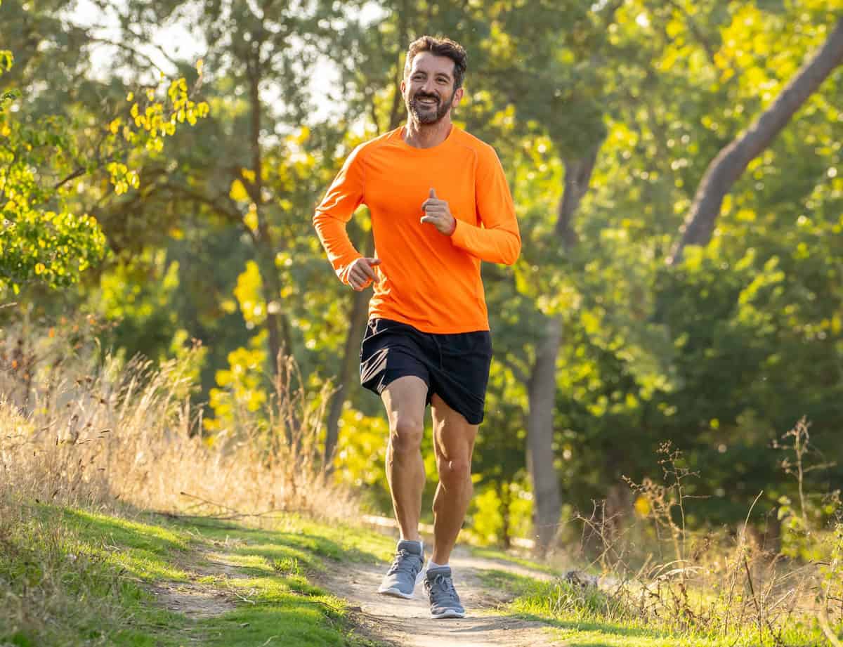 A man doing a long run outside on a dirt path.