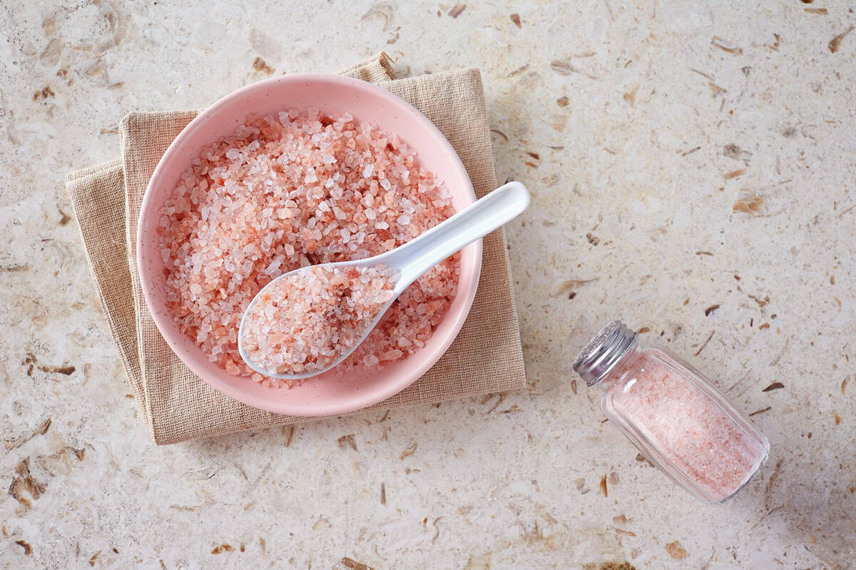 Pink salt in a pink bowl next to a salt shaker.