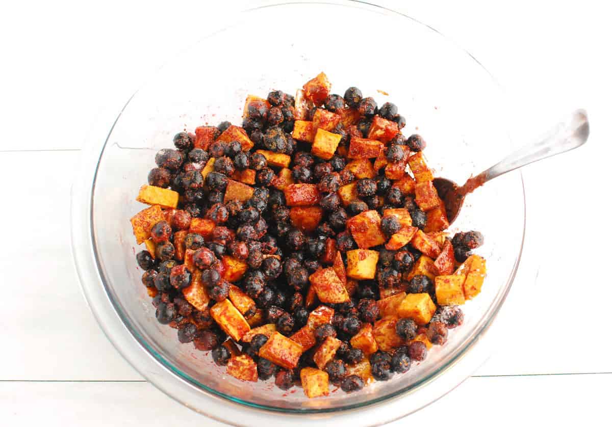 Blueberries, sugar, corn starch, lemon juice, vanilla, cinnamon, and salt combined in a glass mixing bowl.