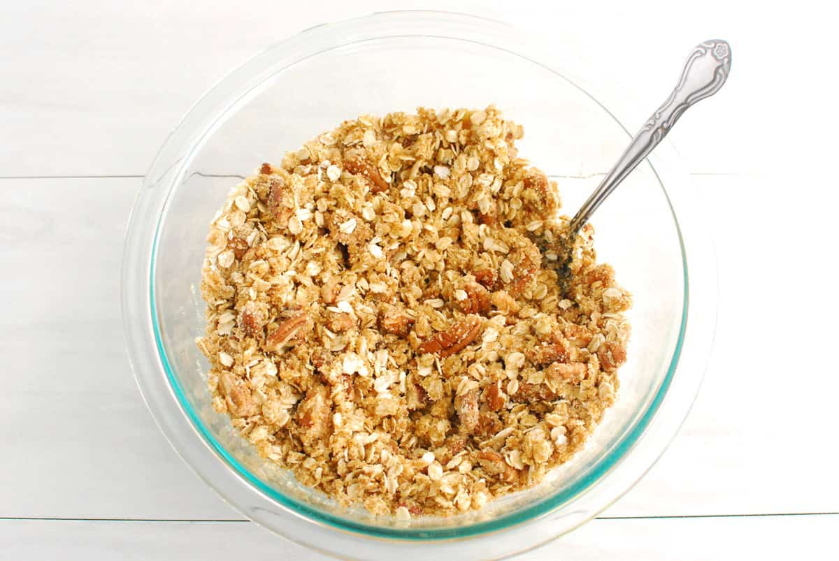 Oats, almond flour, pecans, coconut sugar, salt, and olive oil combined in a glass mixing bowl.