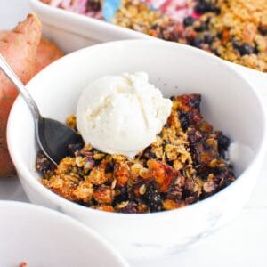 A bowl of sweetpotato blueberry crisp topped with oat milk ice cream.