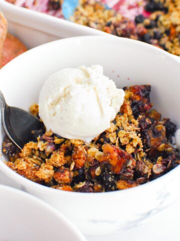 A bowl of sweetpotato blueberry crisp topped with oat milk ice cream.