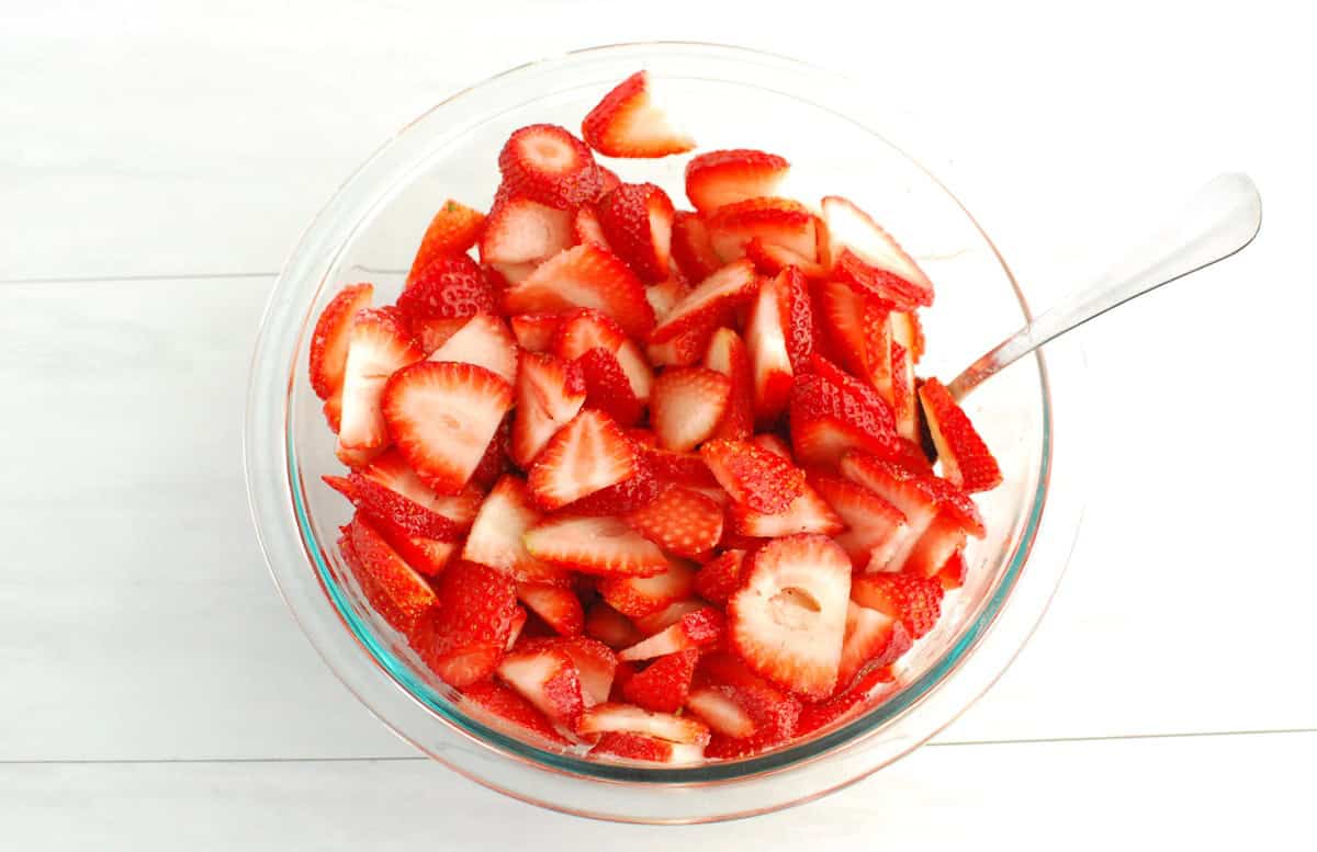 A bowl of strawberries tossed with a small amount of sugar.