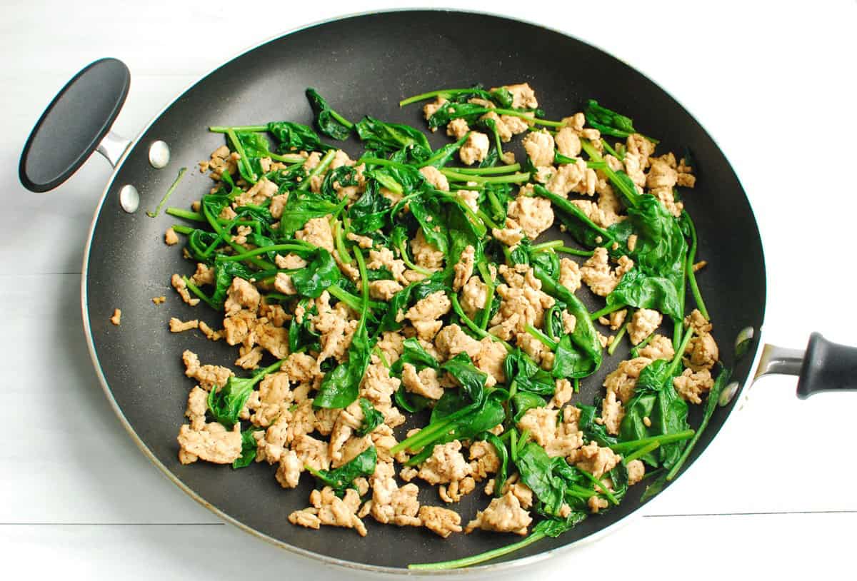 Spinach and ground chicken in a large skillet.