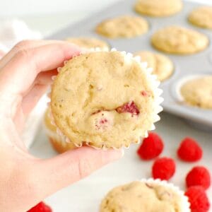 A woman's hand holding a Kodiak Cake raspberry protein muffin.