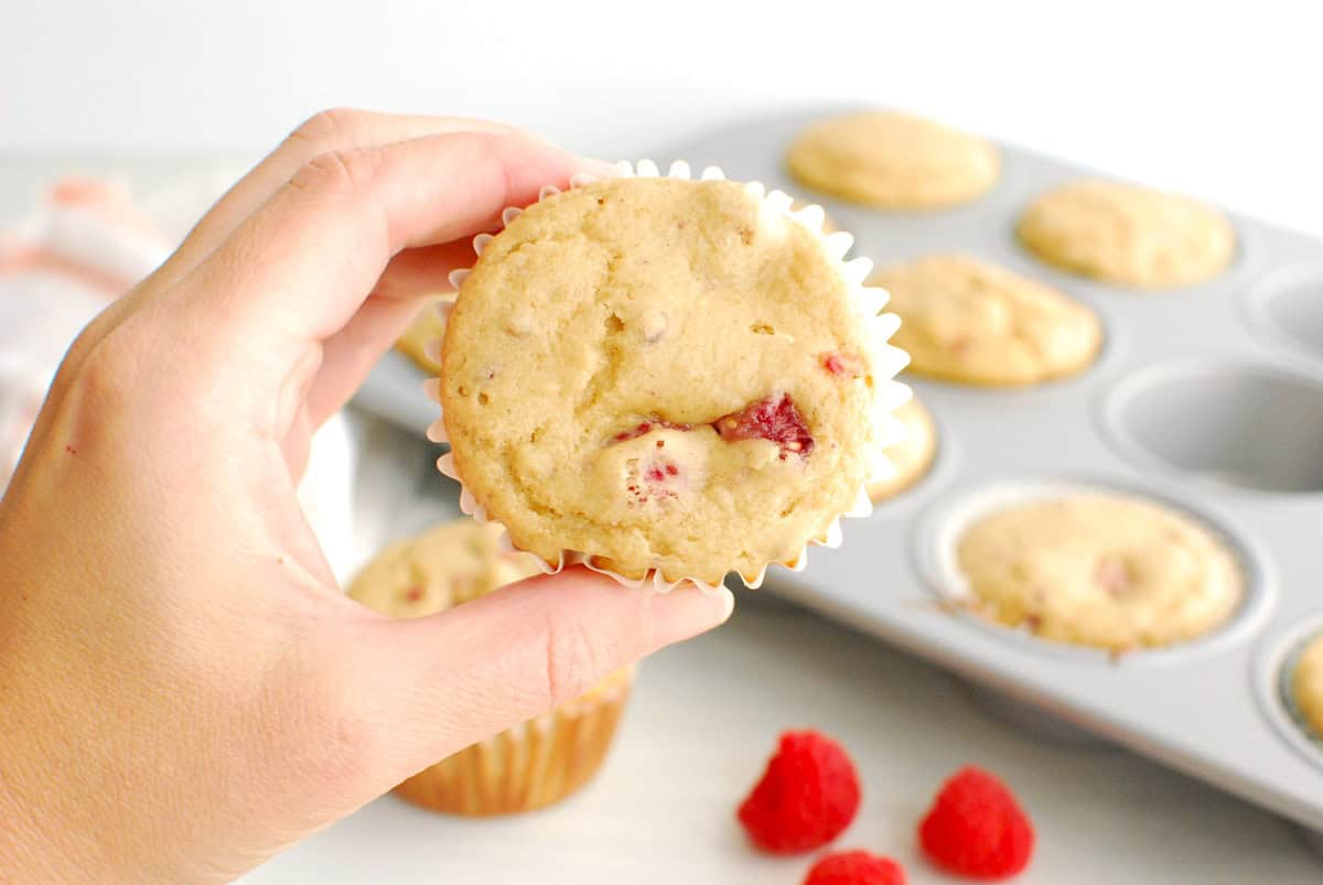 A woman's hand holding a Kodiak Cakes raspberry muffin.