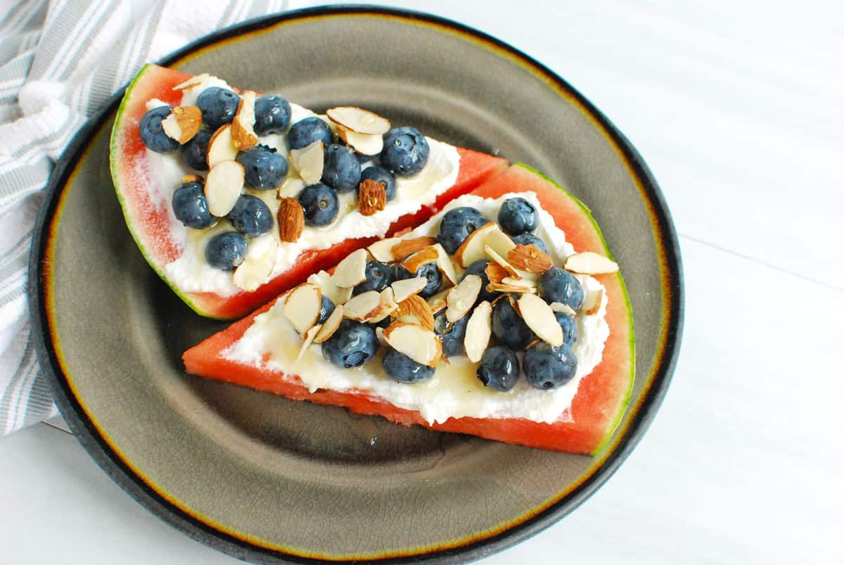Two slices of watermelon ricotta pizza on a plate.