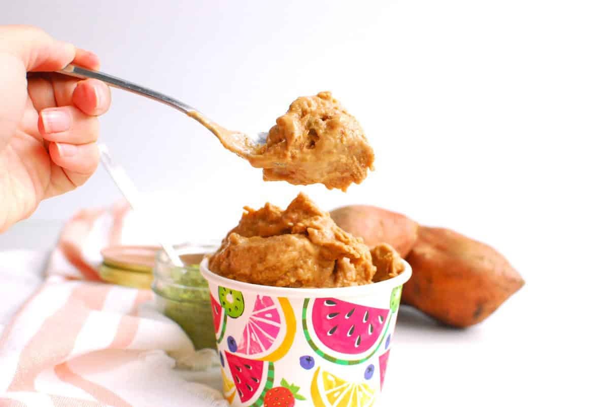 A spoonful of strawberry sweetpotato nice cream being scooped from the cup.