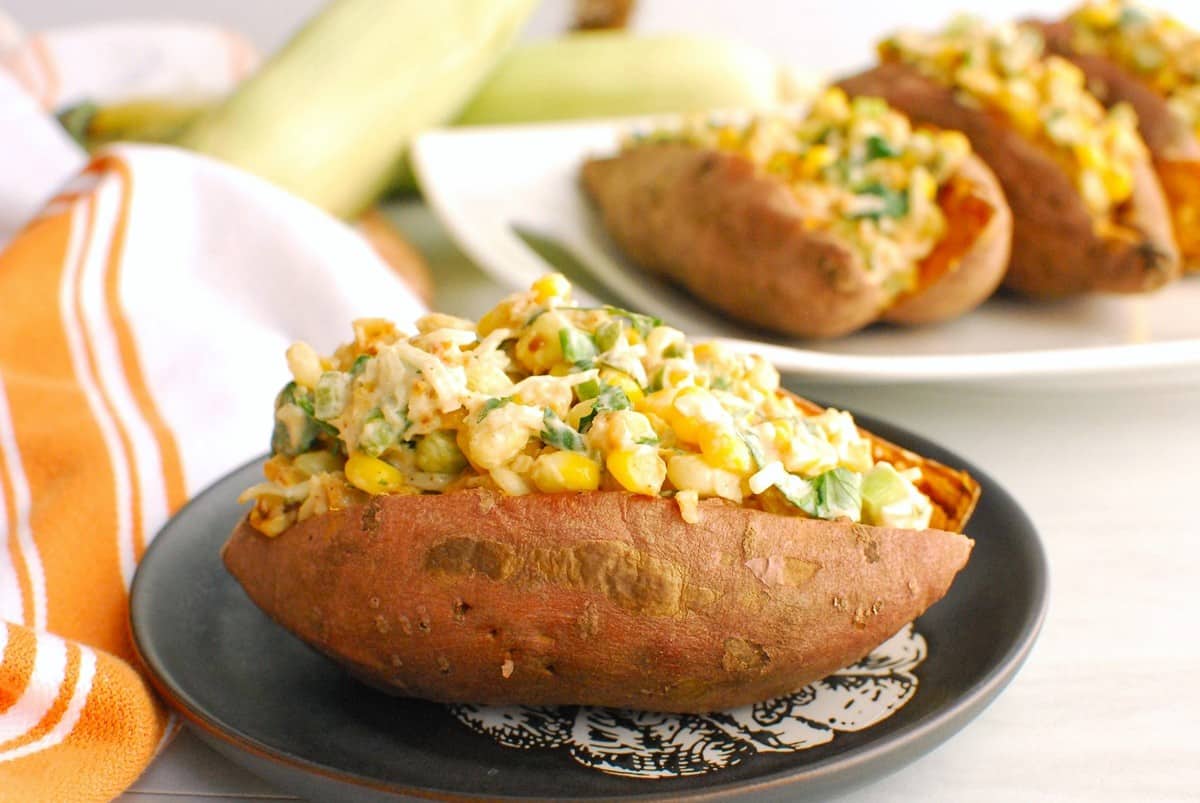 A sweetpotato on a small plate stuffed with the street corn inspired filling.