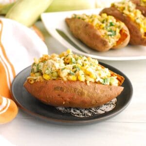A street corn stuffed sweetpotato on a plate next to a napkin.