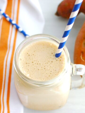 A high protein sweetpotato iced latte in a mason jar with a blue straw.