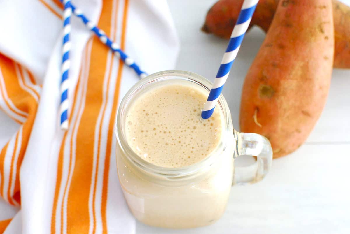 A high protein sweetpotato iced latte in a mason jar with a blue straw.