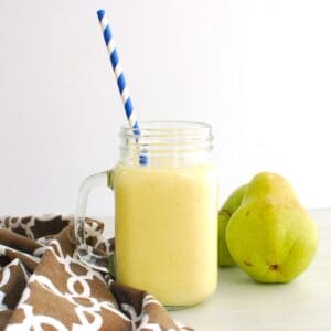 A mango pear smoothie in a mason jar with a straw.