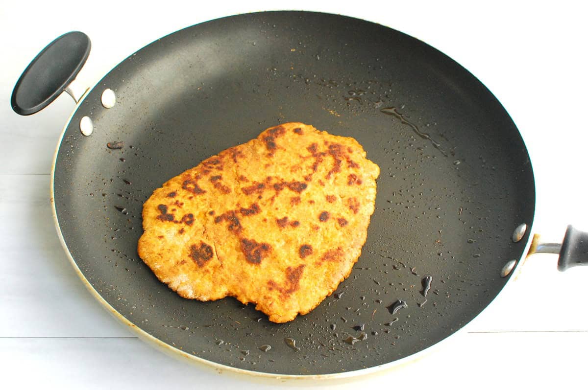 A sweetpotato flatbread cooking in a skillet.