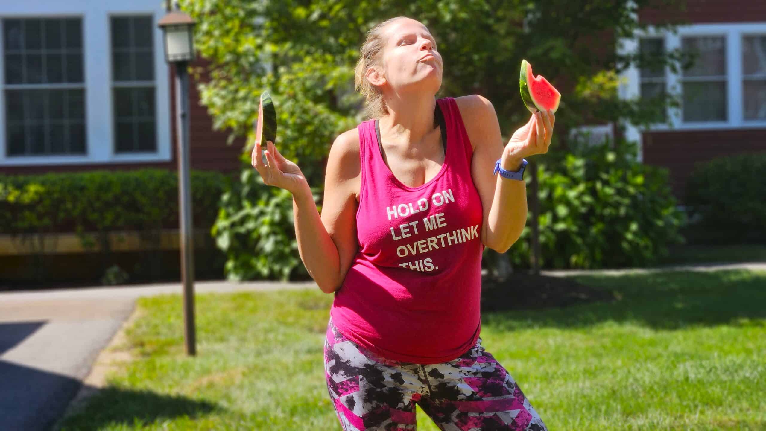 A woman looking blissful eating watermelon after a summer run to rehydrate.