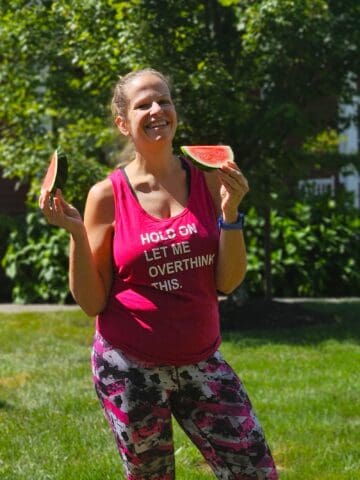 A woman holding two slices of watermelon after a summer run.