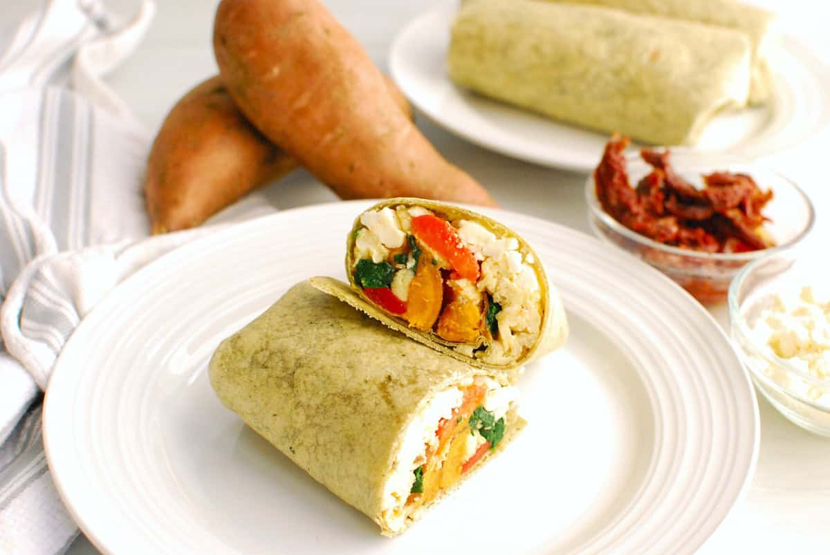 A Mediterranean breakfast burrito cut in half showing the filling.