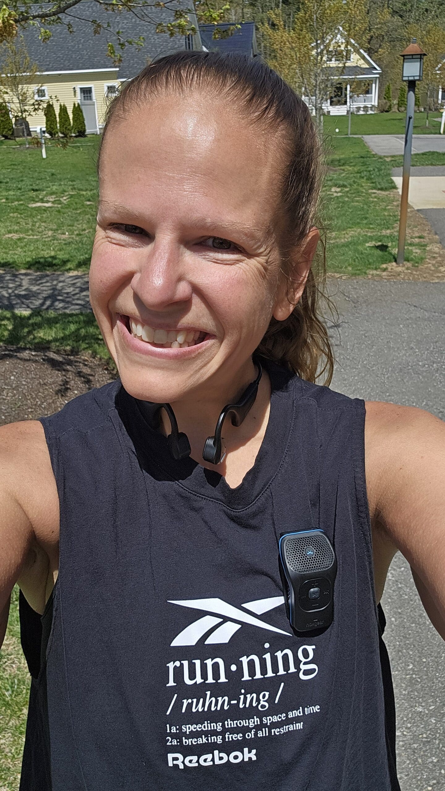 A woman with bone conduction headphones and a mini speaker on her shirt.
