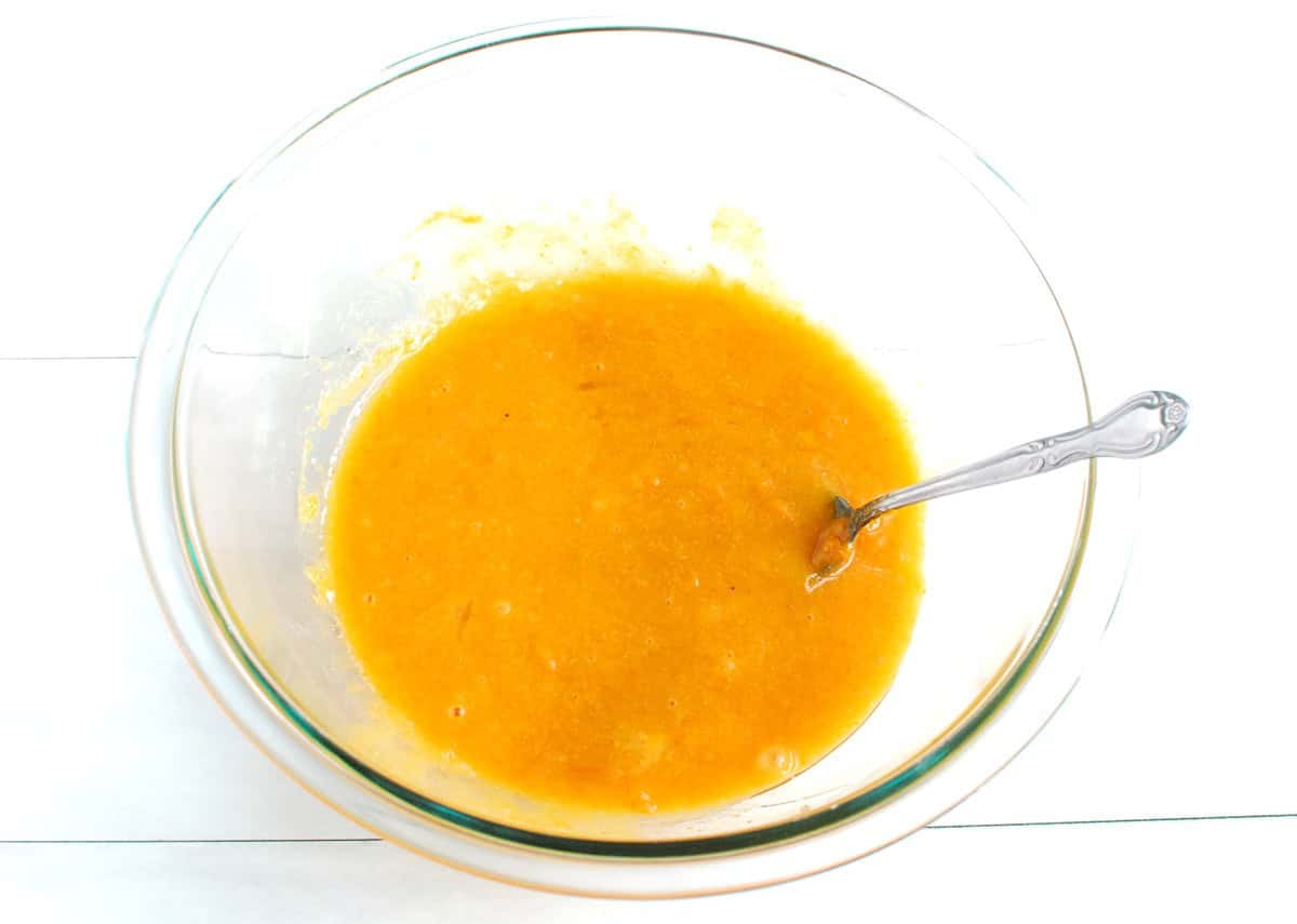 Pumpkin puree, sugar, oil, eggs, and vanilla mixed together in a glass bowl.